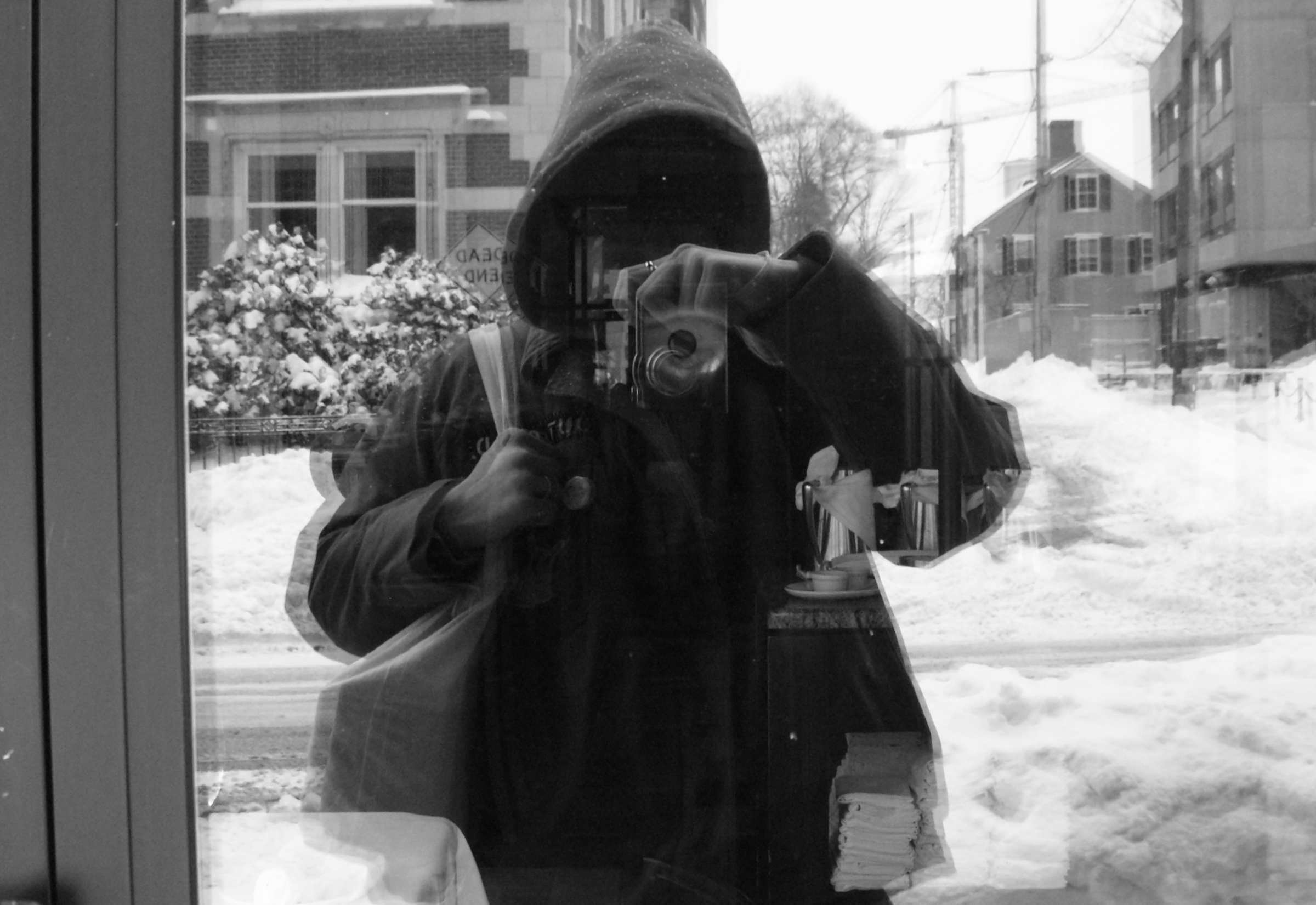 A black and white photo of Henry Pestana taken in the glass of a restaurant.